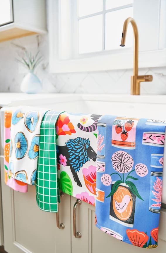 Brightly illustrated tea towels hanging in a kitchen.