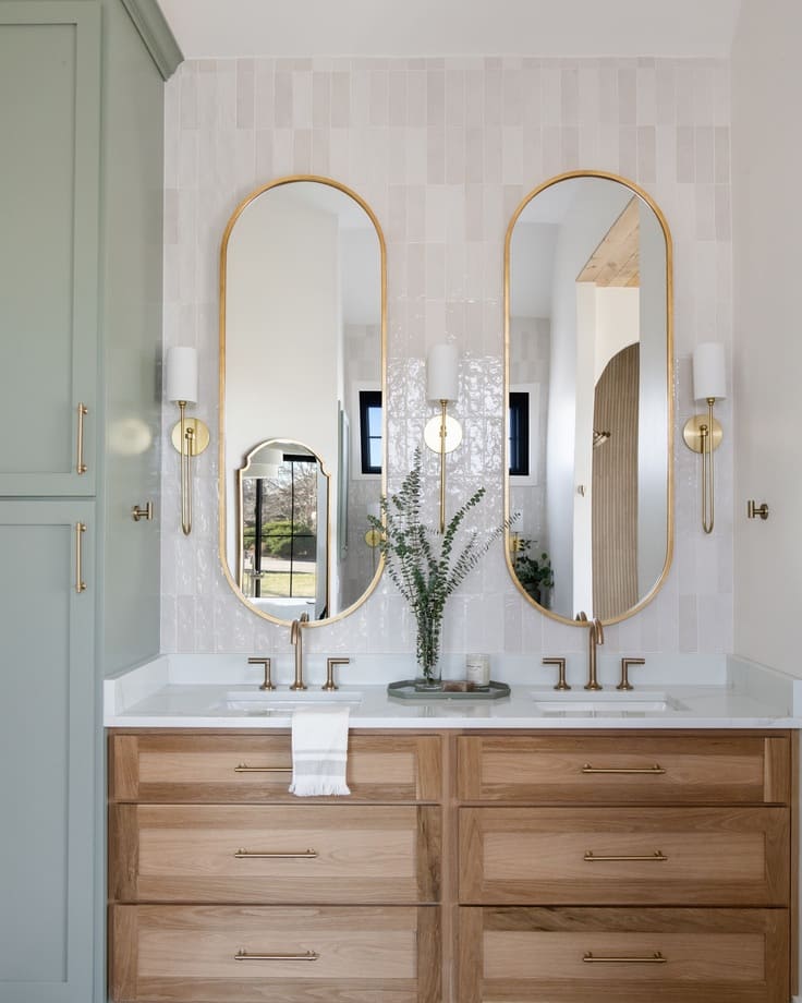 oak double vanity with gold mirrors and sconces