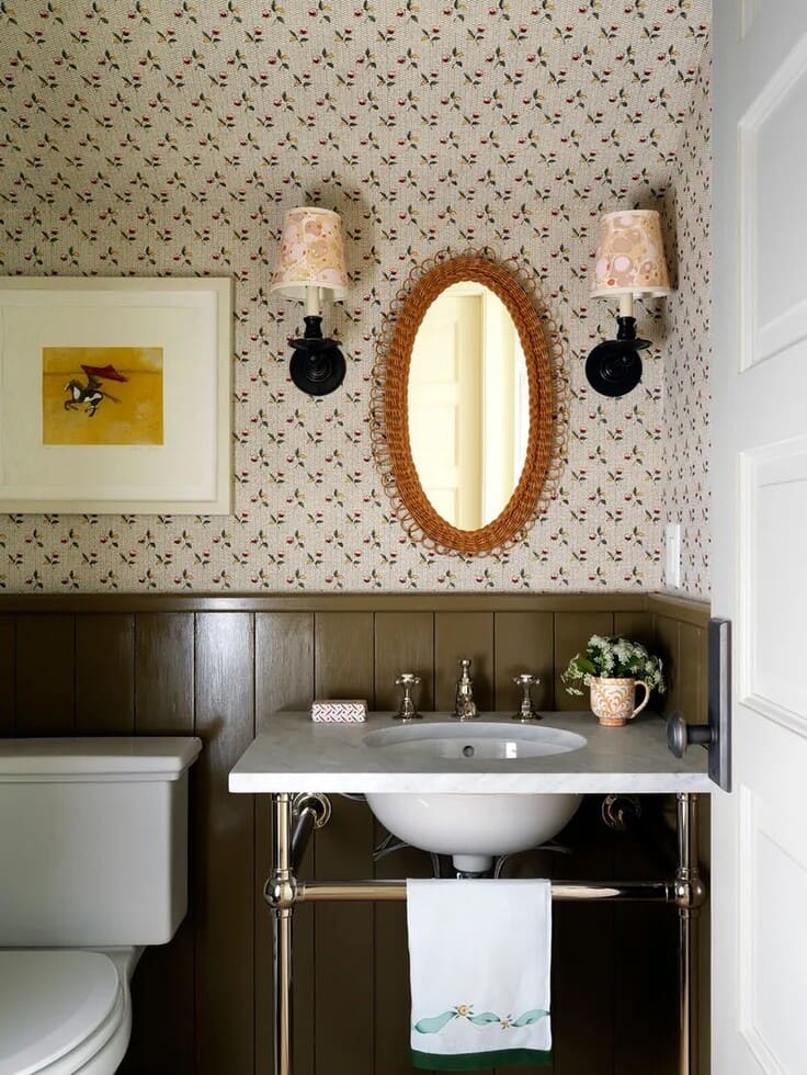 Small floral bathroom wallpaper with olive green wainscoting and wicker mirror