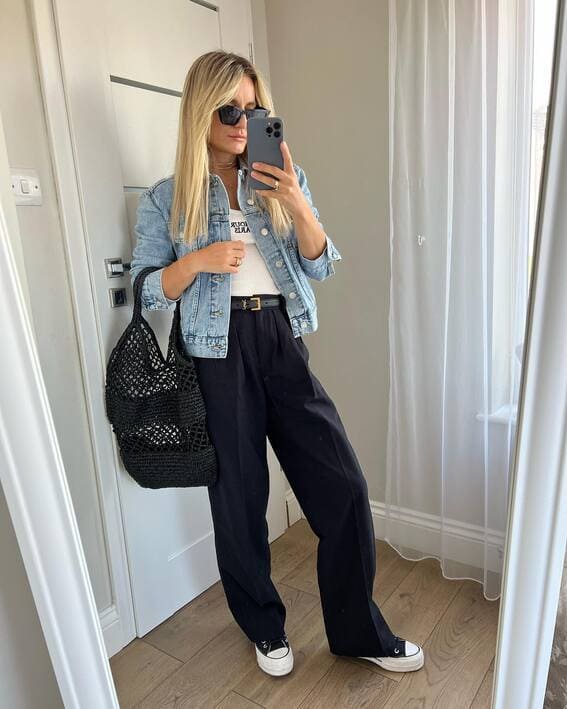 A woman wearing an denim jacket, paired with wide-leg pants and sneakers 