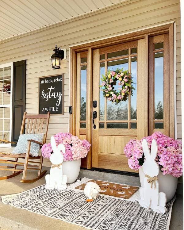 Light wood doors and pink hydrangeas, layered rugs and white wooden bunny cutouts decorate a seasonal front porch.