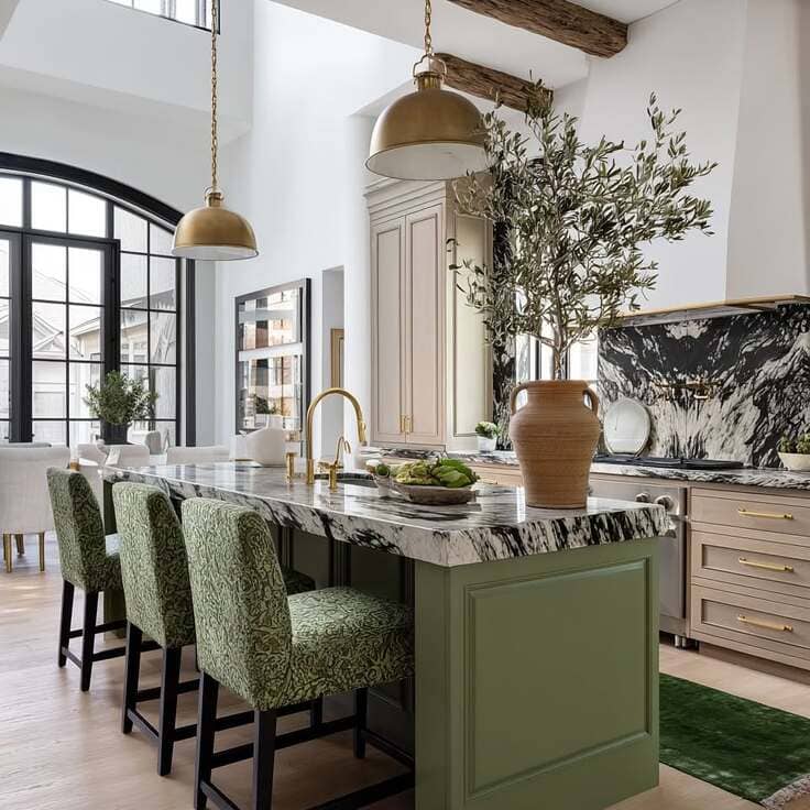 Open-concept kitchen featuring a green paneled island, dramatic black-and-white marble countertops, brass lighting, and leafy green upholstered bar stools