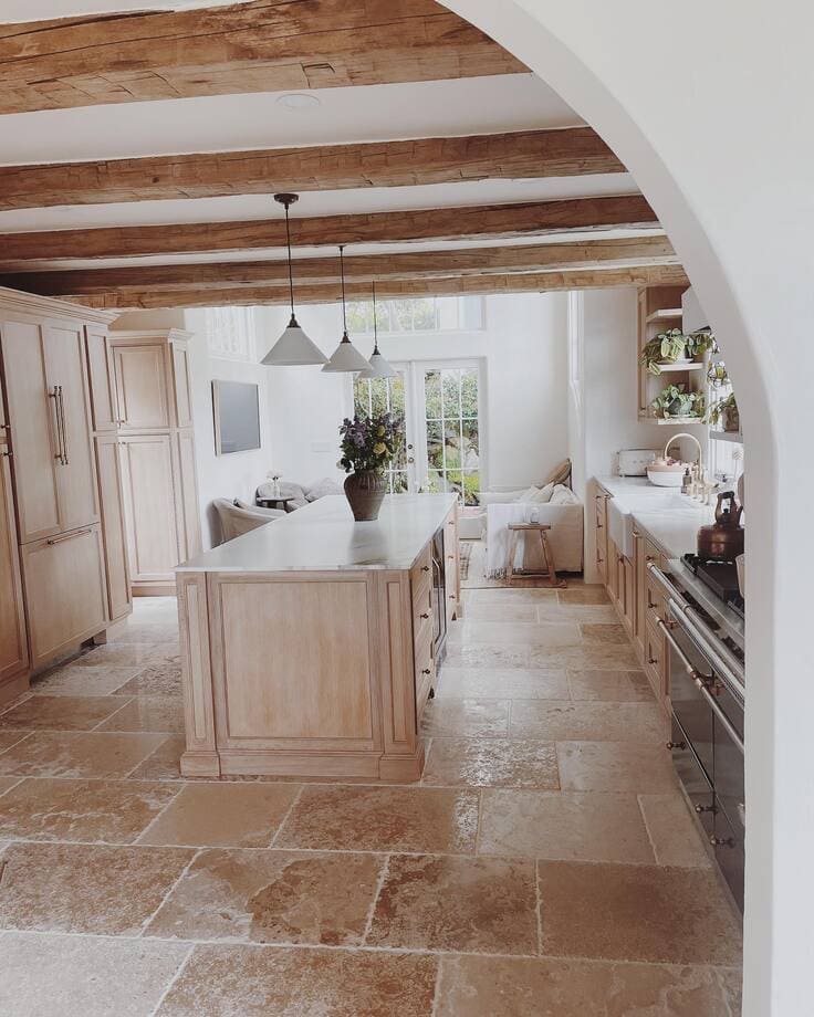 French country kitchen with light wood cabinetry and stone floors
