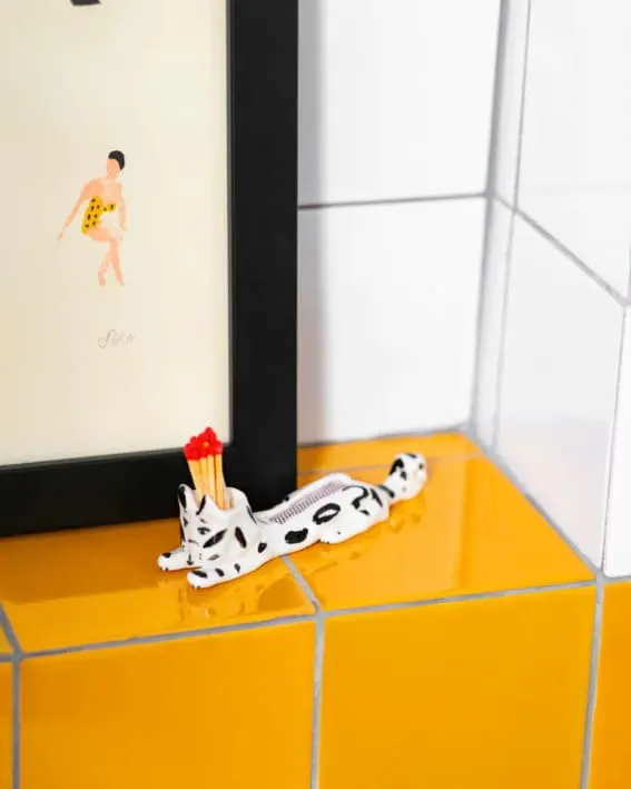 A Dalmatian-patterned matchstick holder on a tiled counter.