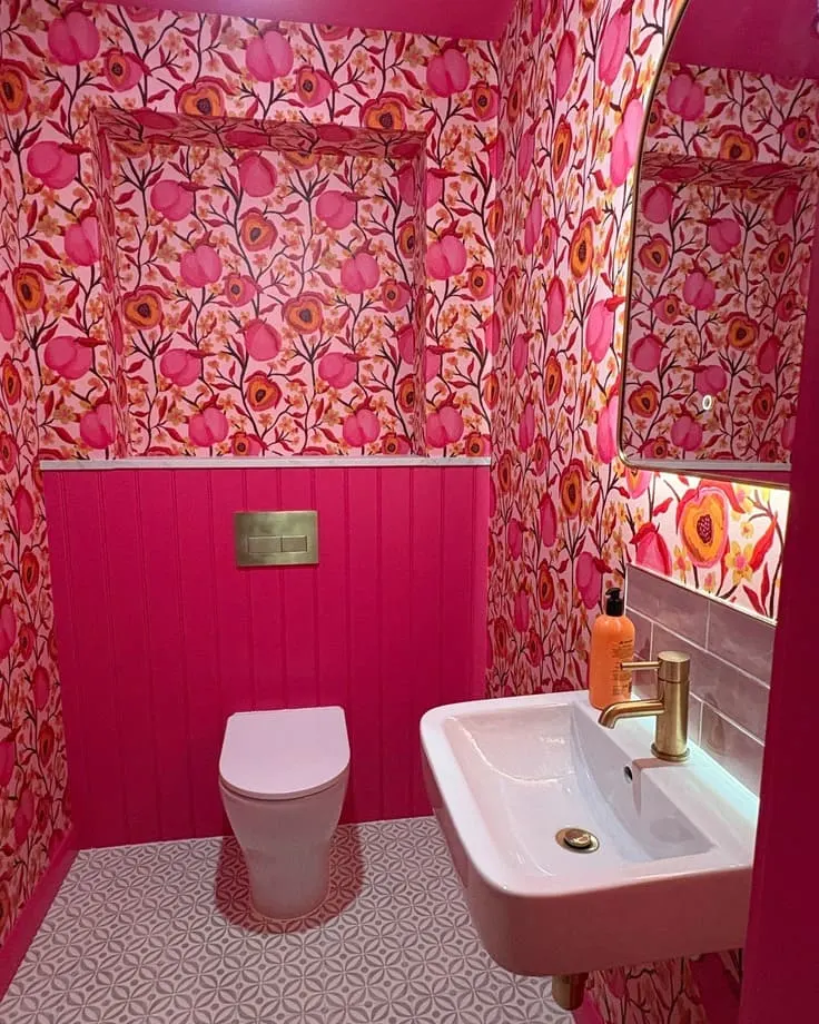 Pink floral bathroom wallpaper with matching paneling and gold fixtures