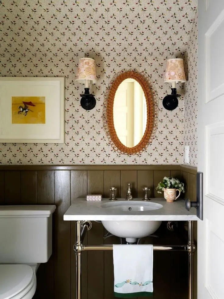 Small floral bathroom wallpaper with olive green wainscoting and wicker mirror