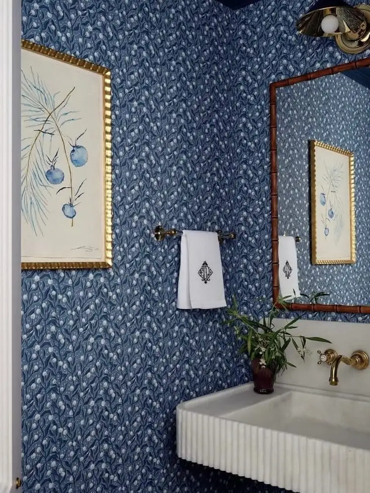 Blue patterned bathroom wallpaper with a fluted sink and gold fixtures
