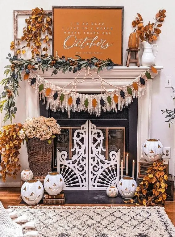 A cozy fall mantel adorned with a layered garland featuring autumn leaves, beads, and macramé, creating a warm, boho-inspired seasonal display. 