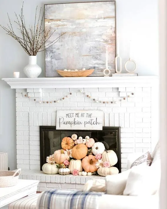 Neutral fall mantel with pastel pumpkins and simple decor accents.