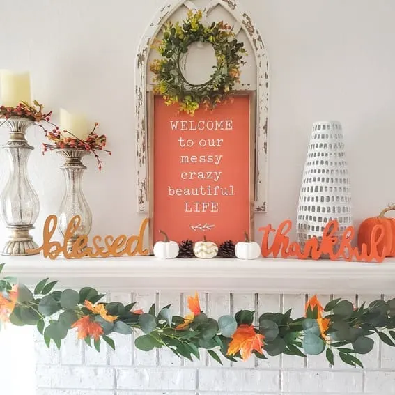 Fall mantel decor with bold orange details and autumn greenery.
