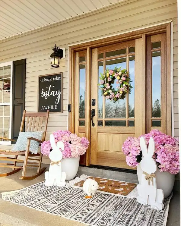 Light wood doors and pink hydrangeas, layered rugs and white wooden bunny cutouts decorate a seasonal front porch.