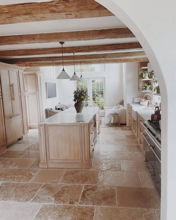 French country kitchen with light wood cabinetry and stone floors